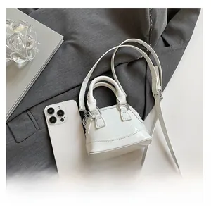 Mini sac coquillage en cuir verni blanc avec un smartphone pour comparer la taille