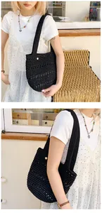 Close-up of black hand-woven crochet tote bag featuring intricate knit texture and gold charm