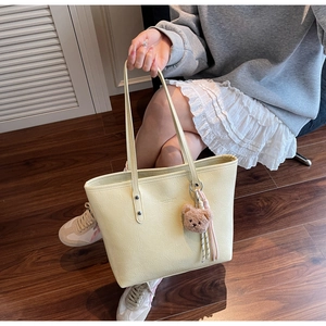 Dettaglio di una borsa tote grande giallo chiaro con ciondolo a orso e finitura in pelle