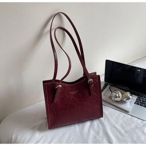 Macro detail of burgundy faux leather tote bag with vintage texture and gold buckle straps