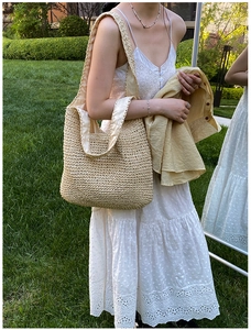 Dettaglio ravvicinato della borsa tote in paglia intrecciata con trama naturale e fodera beige