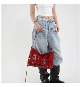 Détail du sac en cuir verni rouge avec rivets argentés et ferrures au style punk