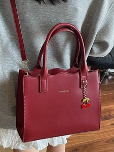 Elegante weinrote Handtasche mit Wellenkante und Kirschanhänger für stilvolle Damen