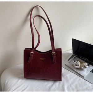 Detail view of burgundy leather tote bag with vintage texture and long shoulder straps