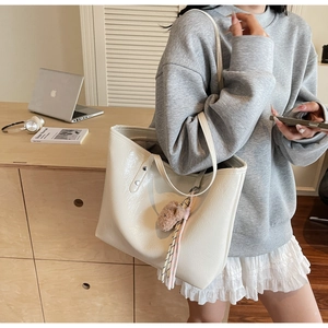 Dettaglio della borsa tote bianco crema con trama in ecopelle e ciondolo a forma di orso