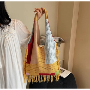 Detailed close-up of bohemian knit tote bag with colorful patchwork and long fringe tassels