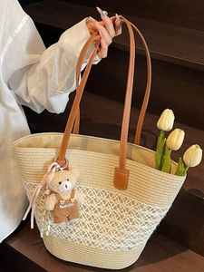Straw tote bag with white mesh pattern, leather handles and cute bear charm decoration
