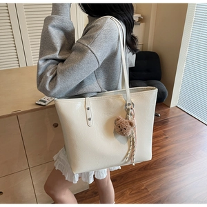 Dettaglio di una borsa tote bianco crema lucida con orsetto di peluche e testo moda