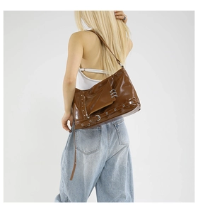 Détail d'un sac punk Y2K marron avec œillets métalliques et boucles argentées