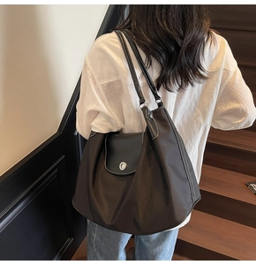 Close-up of black nylon tote bag featuring white contrast stitching and silver metal lock