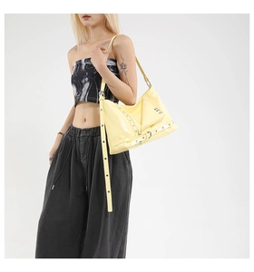 Détail d'un sac punk jaune pâle brillant avec fermetures éclair et boucles style motard
