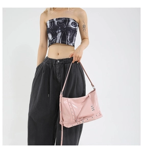 Détail d'un sac cabas en cuir verni rose avec rivets métalliques et zips décoratifs