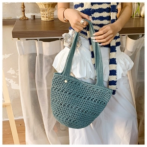 Detail of teal woven knit handbag showing hollow crochet texture and button closure