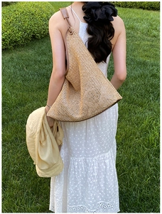 Close-up of woven straw tote bag with brown leather trim and shoulder strap detail