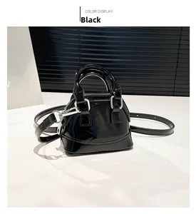 Détail du sac coquille en cuir verni noir brillant avec des crochets en métal argenté