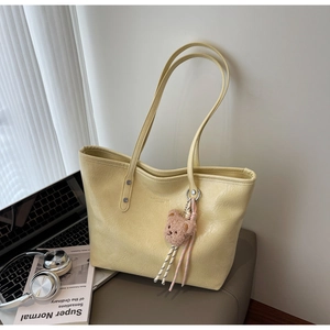 Dettaglio borsa tote giallo crema in pelle testurizzata con ciondolo a forma di orsetto