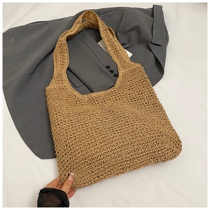 Dettaglio borsa tote in paglia intrecciata a mano con trama naturale e spalline larghe