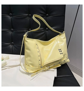 Détail d'un sac cabas en cuir verni jaune avec boucles métalliques et style punk chic