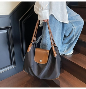 Detail of contrast stitching and silver metal lock on a nylon commuter tote bag