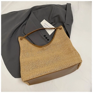 Detailed macro shot of a beige woven tote bag with brown leather straps and metal eyelets