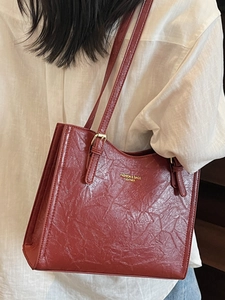 Deep red vintage large tote bag in wrinkled leather shown on shoulder for daily commute