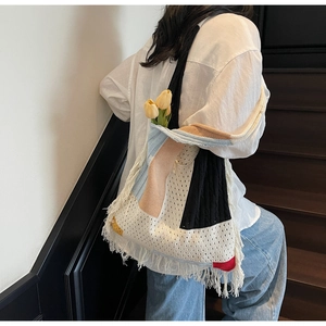 Detail of a retro tassel patchwork knit shoulder bag worn by a model in a minimal setting