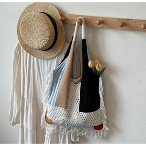 Detailed view of bohemian knit tote bag with colorful patchwork and white tassel accents