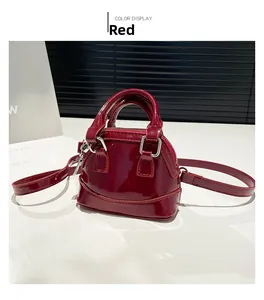 Détail d'un sac coquillage en cuir verni rouge brillant avec des garnitures dorées