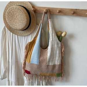 Close-up of bohemian knit tote bag with colorful patchwork patterns and long fringe tassels
