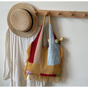 Detailed view of bohemian knit tote bag featuring colorful patchwork and yellow tassels