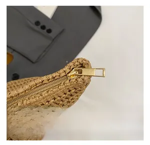 Detail showing the exquisite light gold metal zipper on a woven straw handbag