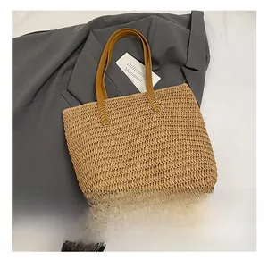 Close-up of woven straw tote bag with brown leather handles and natural fiber texture
