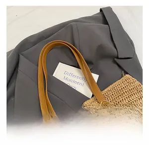 Detail of the brown leather handles and natural straw weave texture on this tote bag