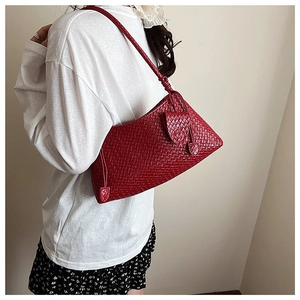 Detail of red handcrafted woven leather underarm bag with intricate texture and strap knot