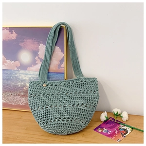 Detail of hand-woven hollow knit tote bag in light green on a wooden surface