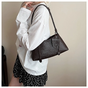 Macro detail of dark brown woven leather texture on elegant shoulder bag with fringe