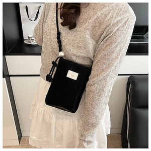 Détail du mini sac bandoulière en similicuir noir avec grande perle et logo nœud papillon