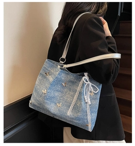 Blue denim tote bag with gold butterfly studs, lace trim and a pearl bow charm detail