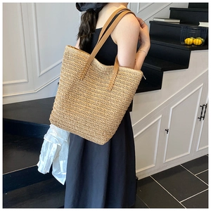 Close-up of woven straw tote bag texture and brown leather shoulder strap detail