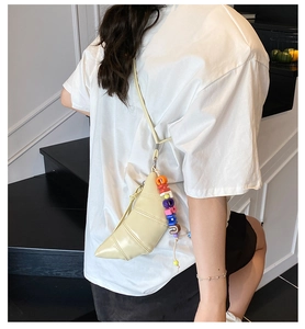 Detail of cream croissant bag featuring colorful letter beads and polished leather finish