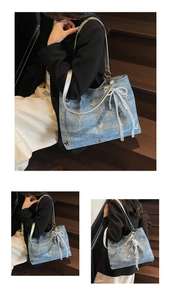 Detail of light blue denim tote bag featuring metallic butterfly and pearl lace bow charm