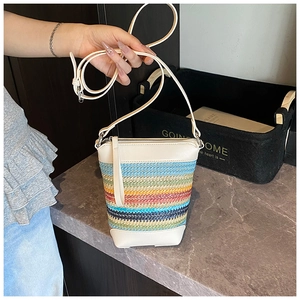 Detailansicht der regenbogenfarbenen Strohtasche mit beigem Lederbesatz und Gurt