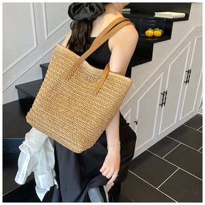 Detailed view of handmade woven straw tote bag with brown faux leather shoulder straps