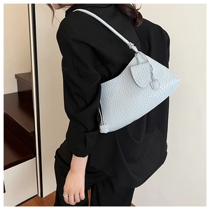 Detail of light blue woven leather shoulder bag with knotted strap and modern texture