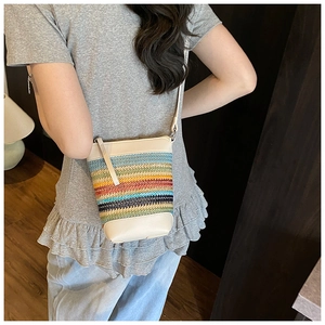 Detailaufnahme der gestreiften Regenbogen-Strohtasche mit cremefarbenem Leder