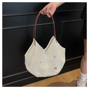 Detail of hollow woven tote bag featuring colorful miniature bows and fine cotton texture