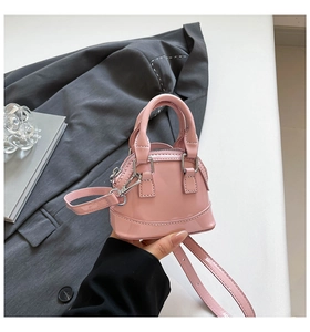 Detail of a mini pink patent leather shell bag with silver hardware and detachable strap