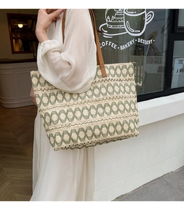 Detail of woven tote bag with green geometric patterns and brown leather straps
