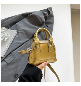 Detailed view of mini metallic shell bag featuring glossy texture and top handle