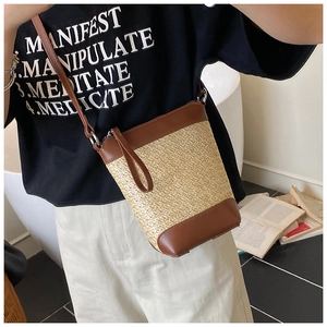 Detail der handgewebten Stroh-Umhängetasche mit braunem Lederbesatz am Frauenmodell